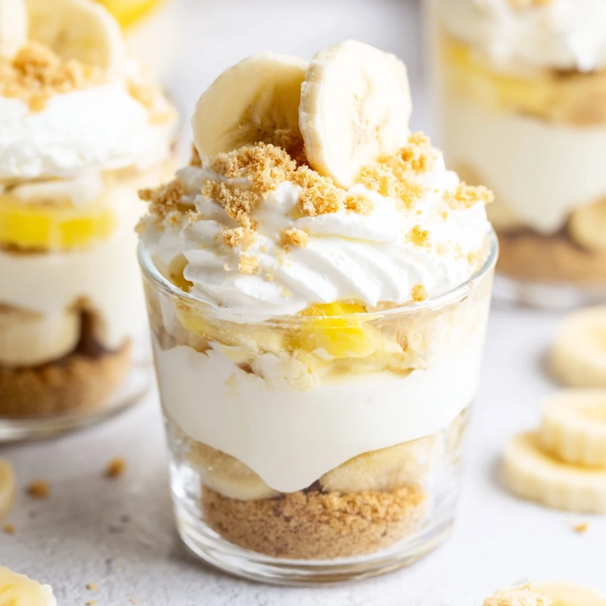 Creamy no bake banana pudding cheesecake cups with layered filling and fresh banana slices on top