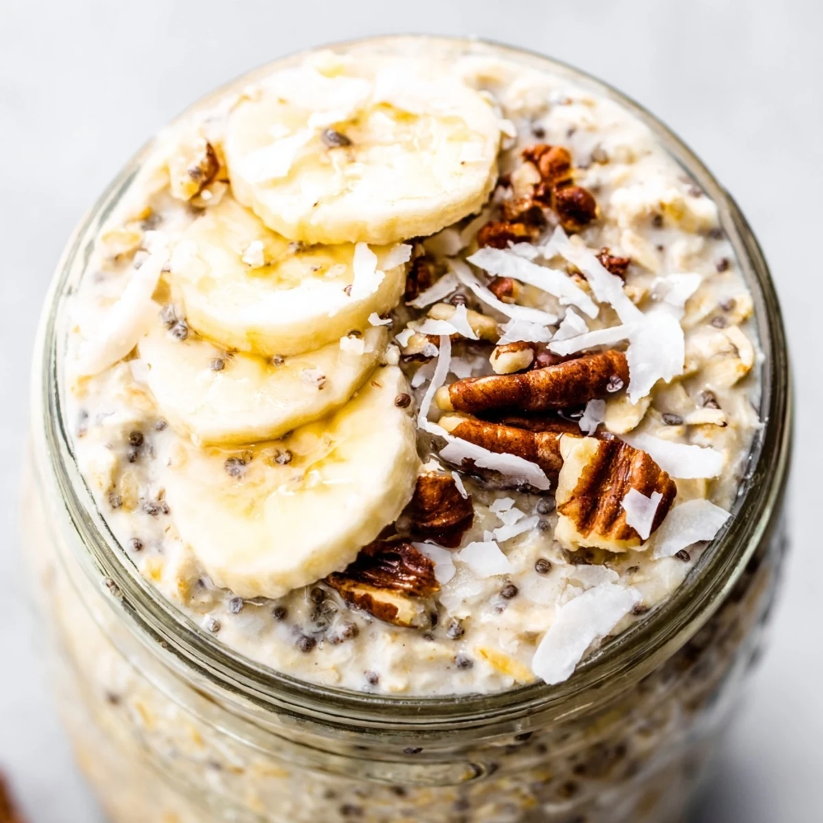 Thick Coconut Cream Pie Overnight Oats served chilled with banana slices and a sprinkle of shredded coconut