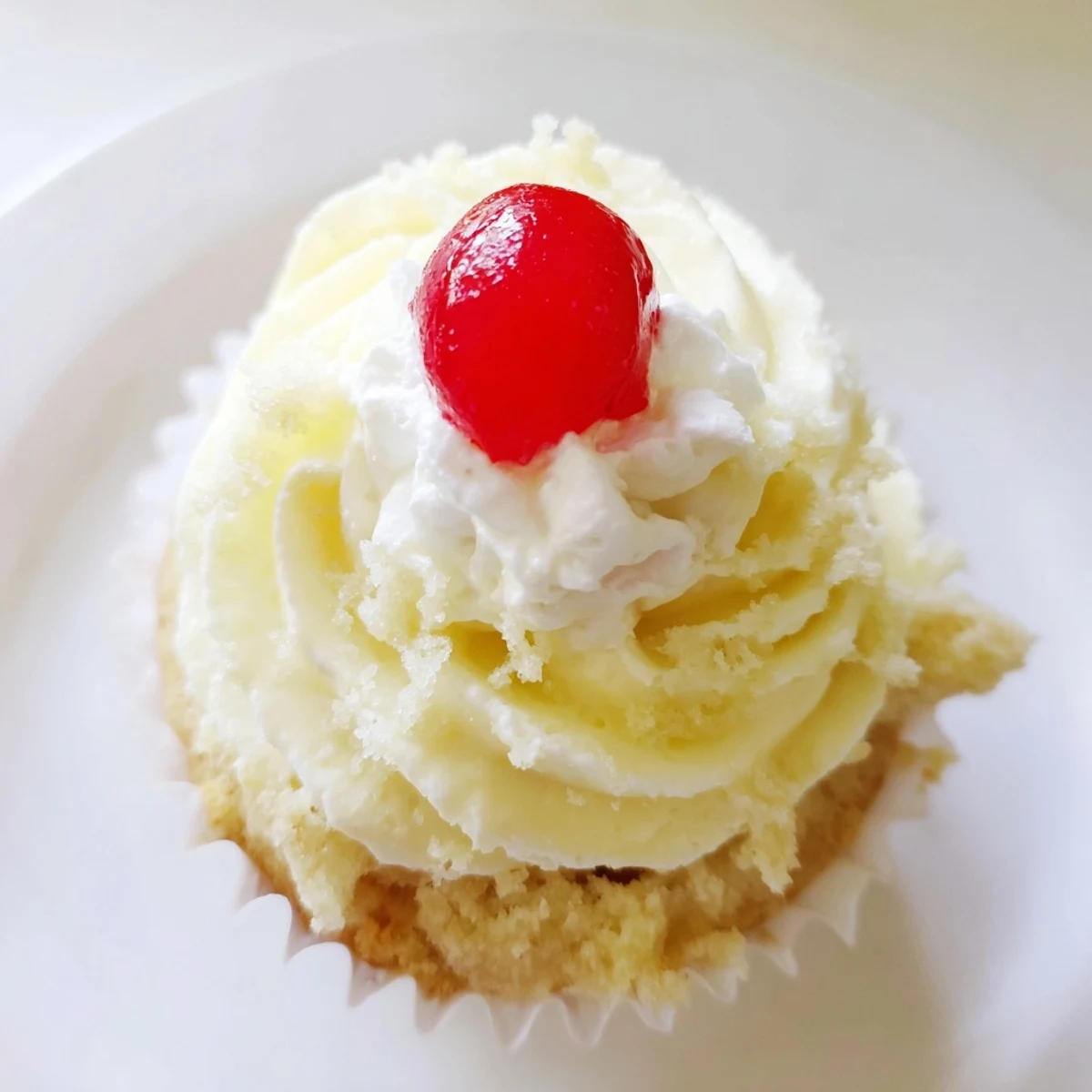 Moist banana milkshake cupcakes topped with creamy vanilla frosting and bright red maraschino cherries
