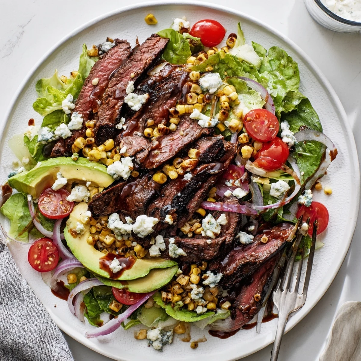 Sliced balsamic steak draped over crisp greens with crumbled Gorgonzola and grilled corn
