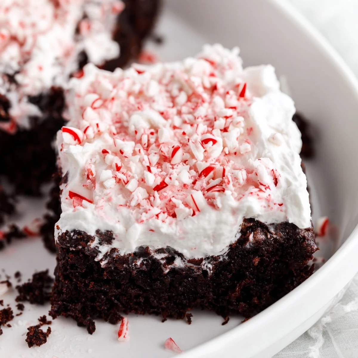 Holiday-ready Peppermint Poke Cake garnished with chocolate shavings, peppermint pieces