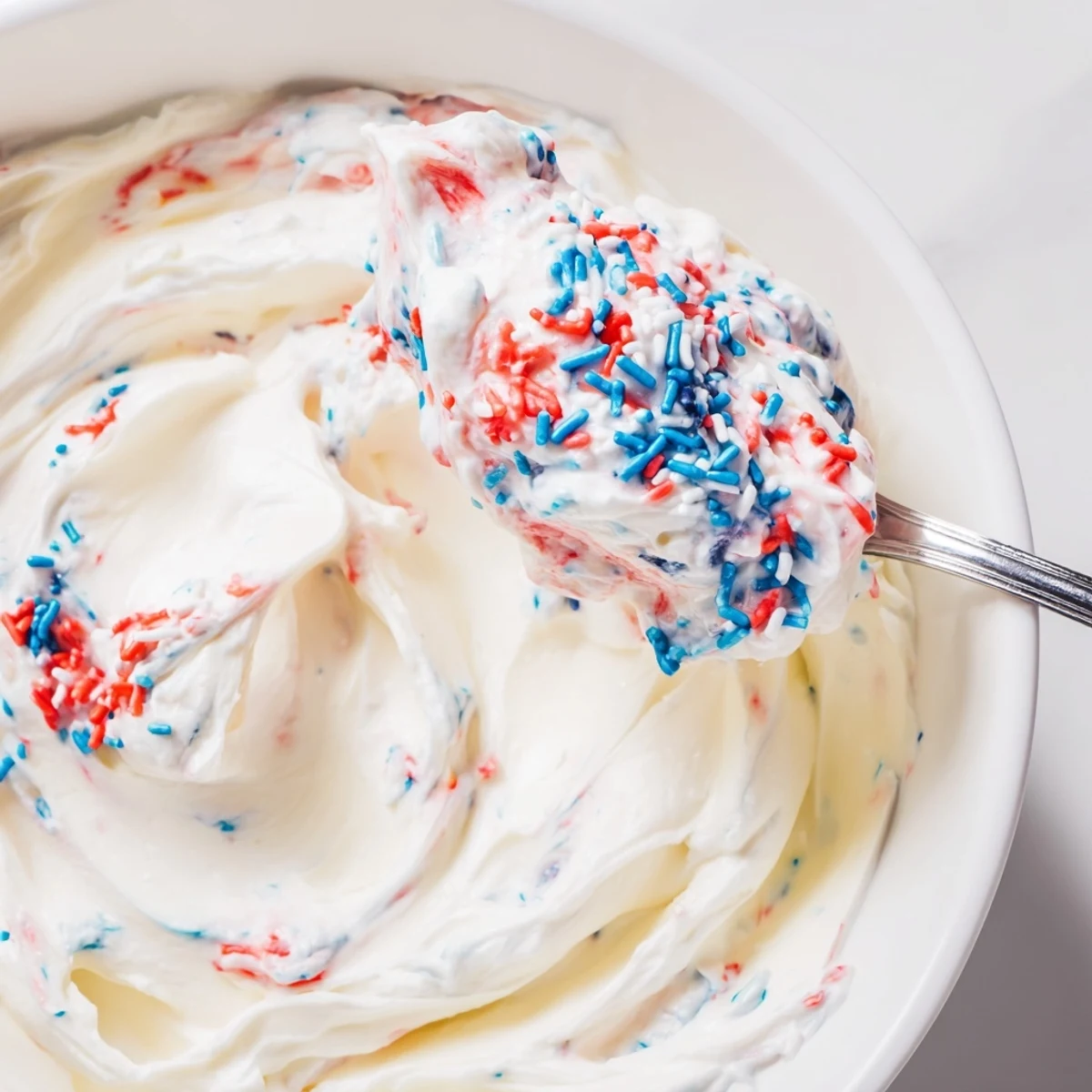 Red White And Blue Funfetti Dip in bowl with sprinkles, ready for dipping