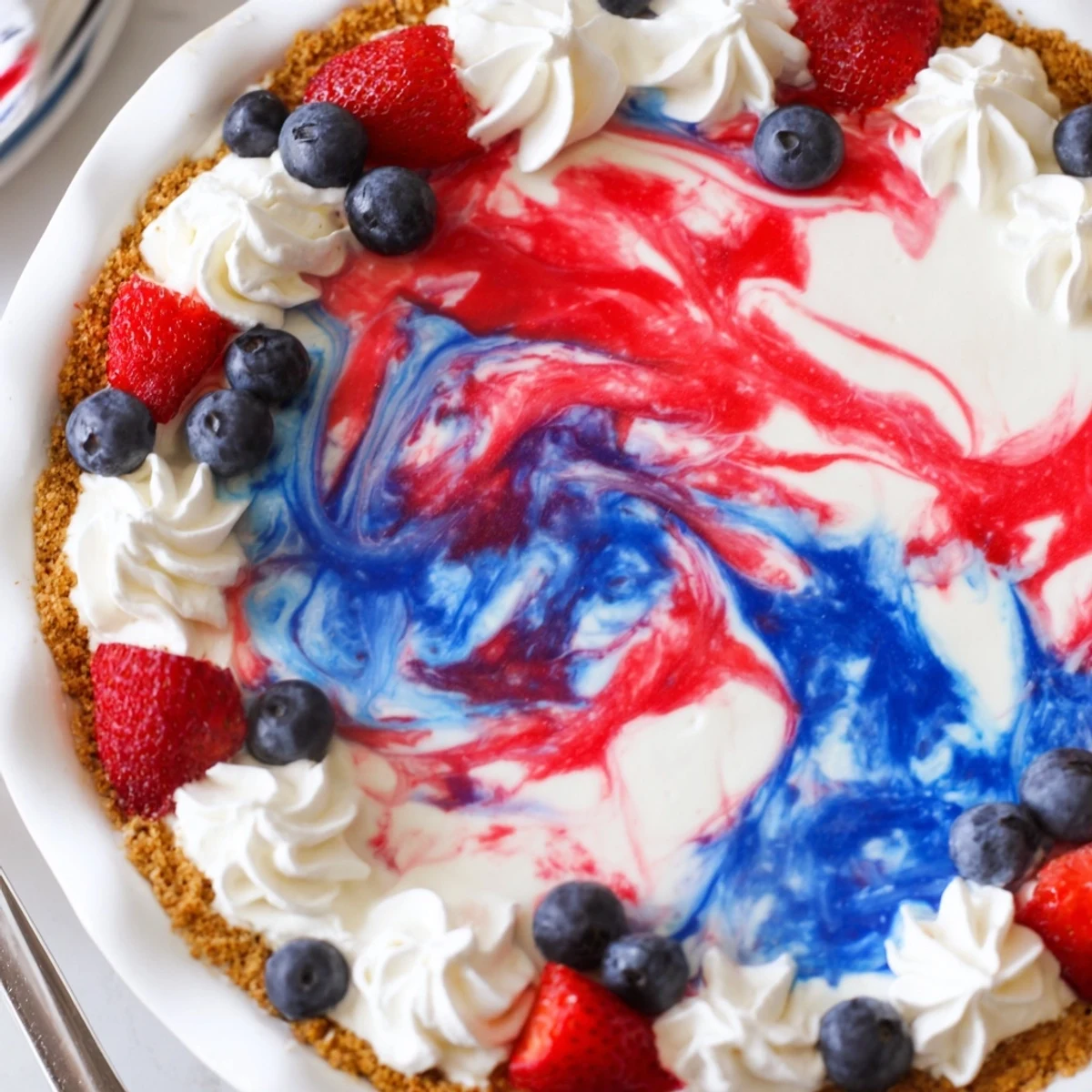 Sliced Patriotic Red White And Blue Swirl Pie chilled, topped with fresh berries.