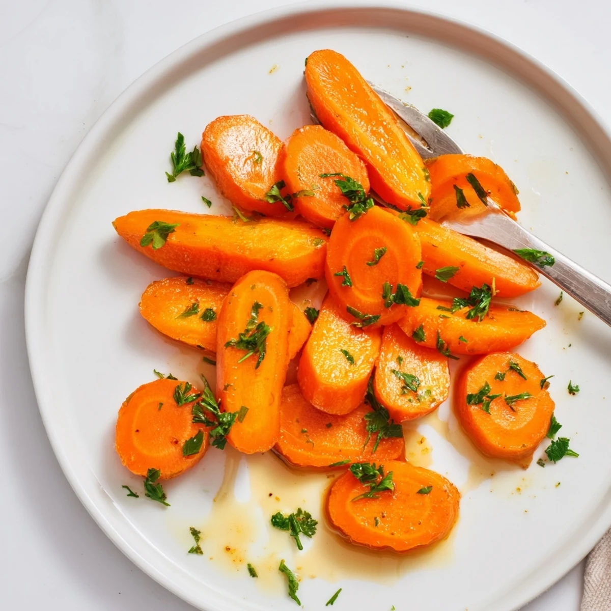 Golden honey glazed carrots arranged on a white serving plate with fresh parsley garnish