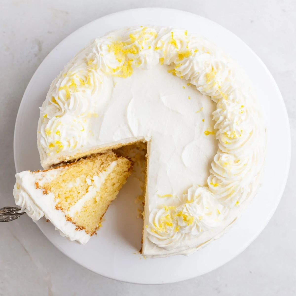 Golden Lemon Birthday Cake with fluffy white cream cheese frosting and fresh lemon zest garnish