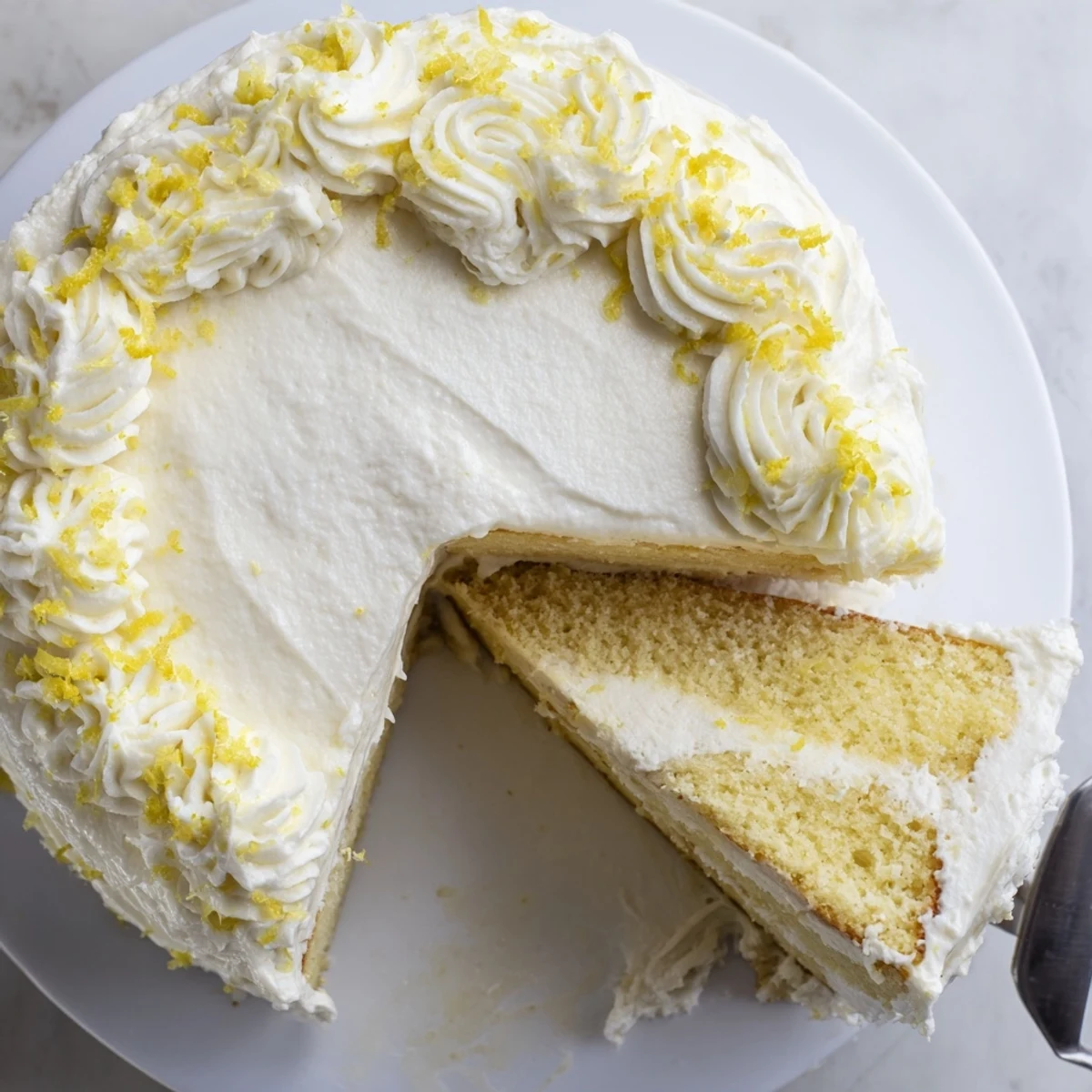 Two-layer Lemon Birthday Cake sliced to reveal moist yellow crumb and tangy citrus cream cheese frosting