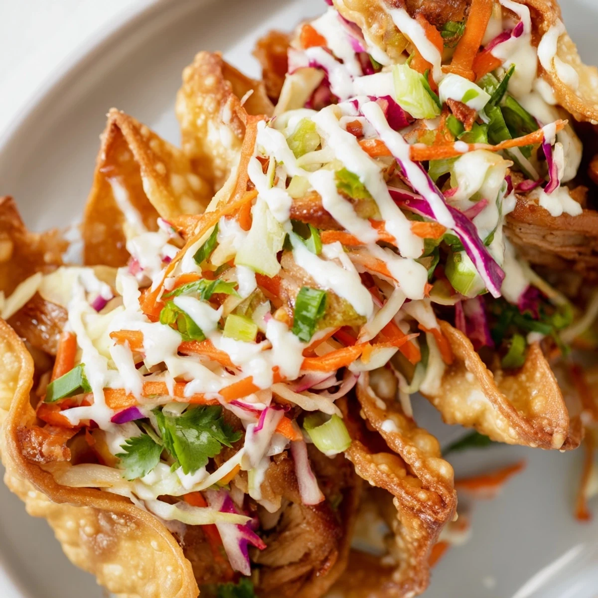 Fusion Asian chicken wonton tacos topped with fresh cabbage slaw and spicy creamy sriracha drizzle