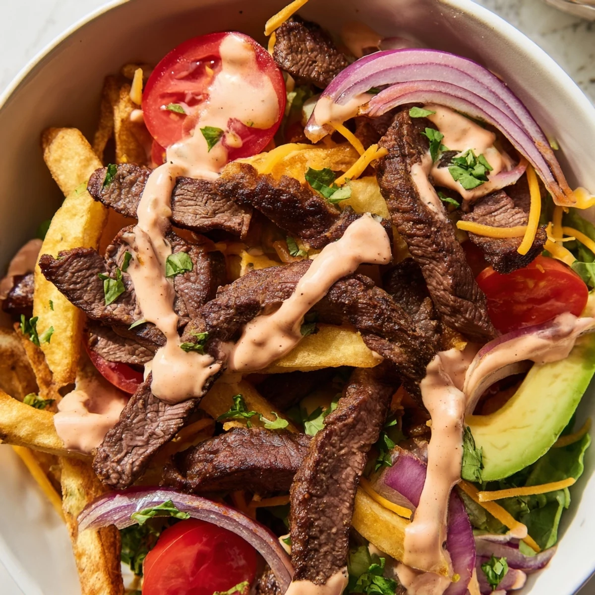 Juicy steak strips and crispy fries bowl drizzled with smoky paprika sauce
