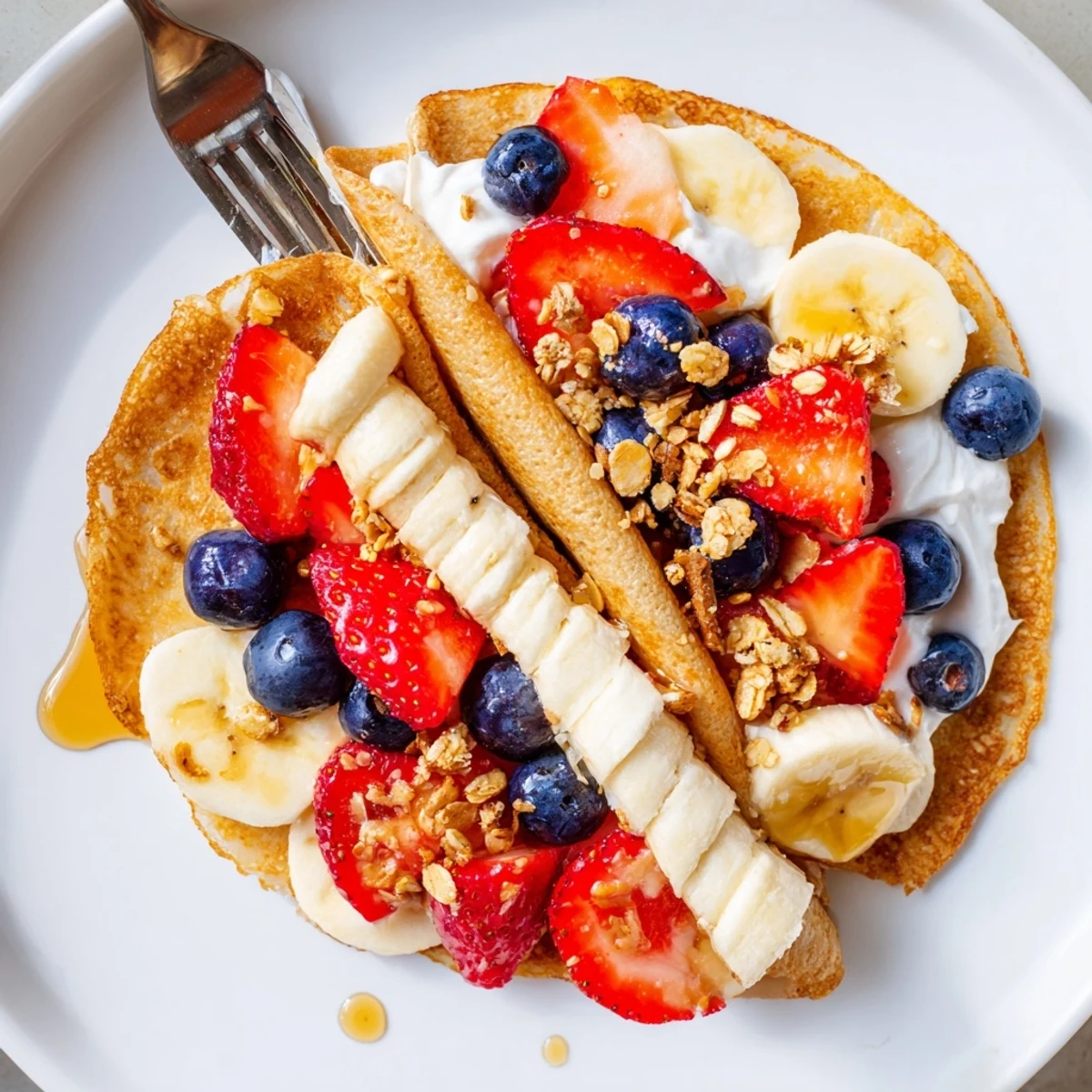 Golden pancake tacos filled with fresh strawberries and drizzled maple syrup on a rustic plate