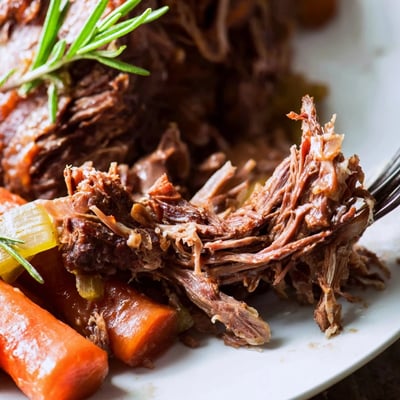 Close-up of Slow Cooked Beef Shank with Rosemary and Thyme served over creamy mashed potatoes.