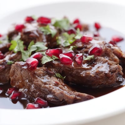 Slow-cooked Braised Lamb Shoulder with Pomegranate Molasses in a deep Dutch oven, surrounded by tender carrots and onions in a rich sauce.