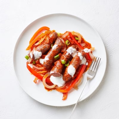 Hearty Sweet and Savoury Sausage Curry simmered in a skillet, featuring tender pork sausages and vibrant red bell peppers.