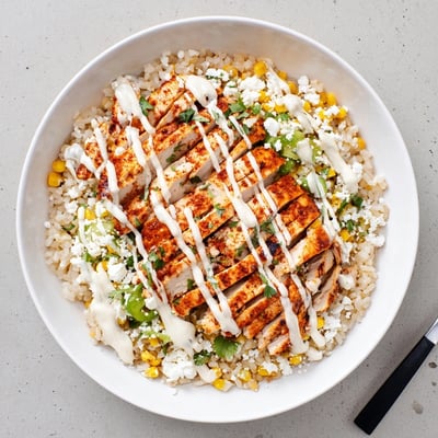 Sliced grilled chicken over charred corn rice bowl drizzled with tangy lime sauce