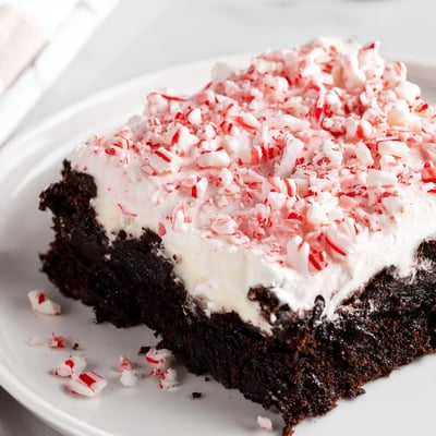 Slice of Peppermint Poke Cake showing pudding-filled holes and minty crumbs