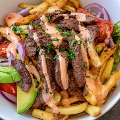 Steak strips crispy fries bowl loaded with avocado tomatoes and melted cheddar